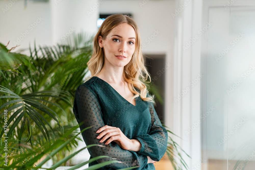 Female entrepreneur with arms crossed standing in office Female entrepreneur with arms crossed standing in office