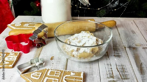 A young woman sprinkles flour onto the raw dough for a traditional festive Christmas cookie. Side view.