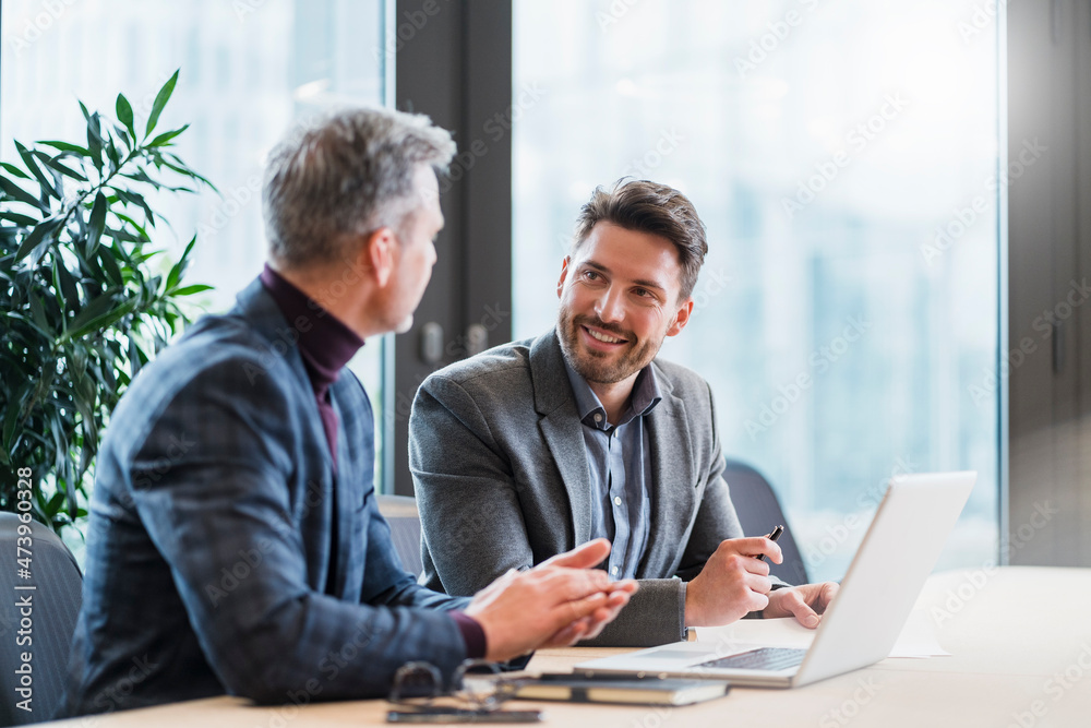 Business people with laptop talking in meeting at work place Business people with laptop talking in meeting at work place