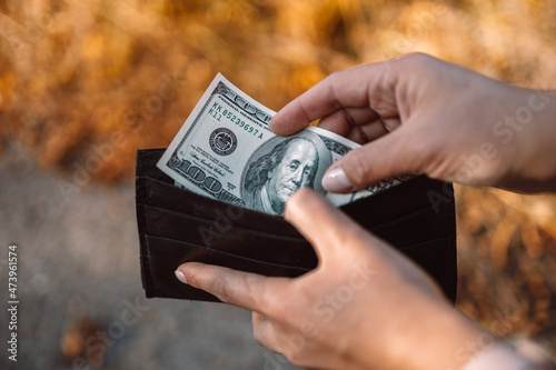 Person taking out dollars money from her pocket wallet. Counting money, economy concept, money distribution photo