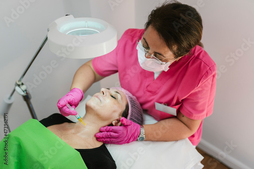 Aesthetician giving biorevitalization treatment to mature woman at clinic photo