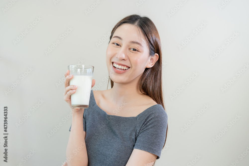 Happy, asian young woman, girl drinking a glass of white fresh, warm or hot dairy milk for calcium, vitamin wholesome good nutrition in morning. lifestyle, product healthy people, Isolated background. Happy, asian young woman, girl drinking a glass of white fresh, warm or hot dairy milk for calcium, vitamin wholesome good nutrition in morning. lifestyle, product healthy people, Isolated background.