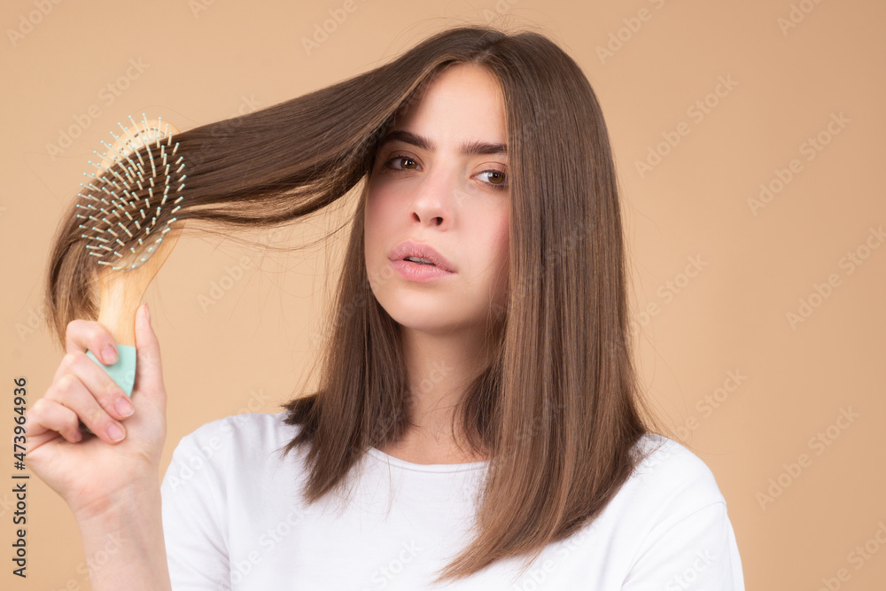Fototapeta premium Attractive woman combing hair. Beautiful girl with hair comb combs hair. Haircare concept.