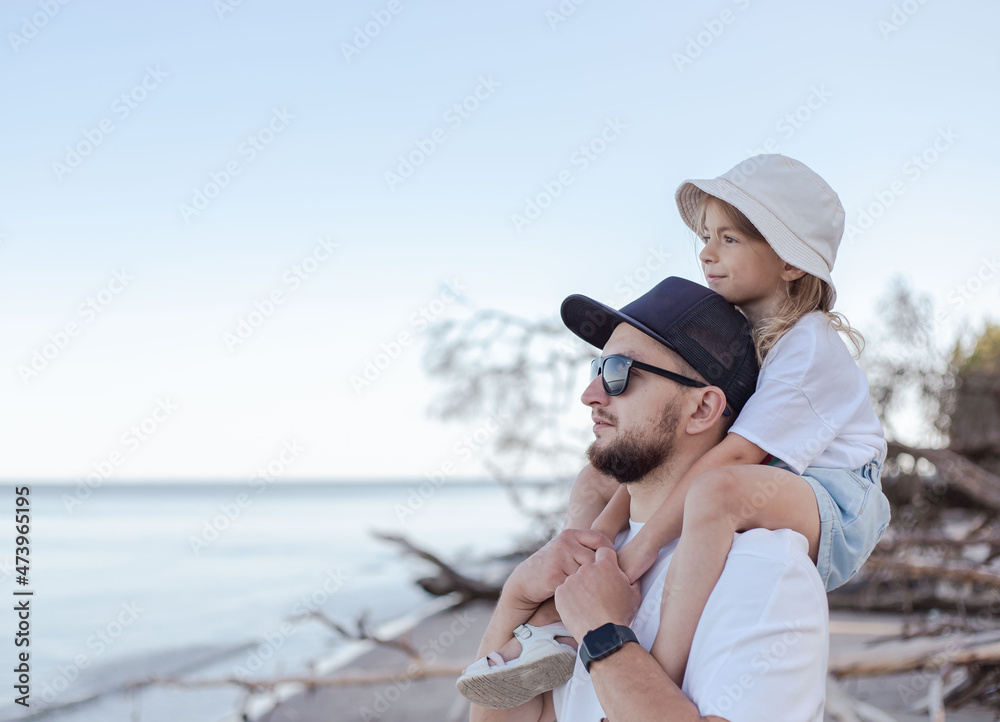 Father holding daughter on his shoulders at the beach.