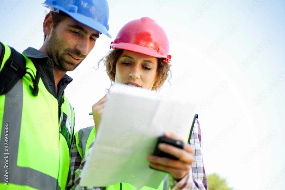 Male and female engineers discussing while holding document