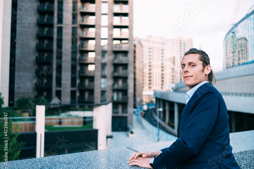 Businessman staring while leaning on retaining wall photo