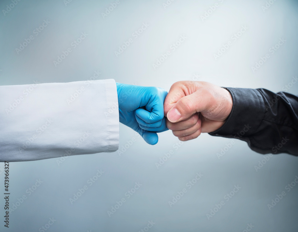 Female healthcare worker giving fist bump to male patient against white background Female healthcare worker giving fist bump to male patient against white background