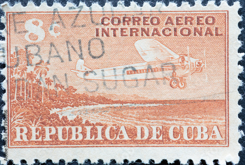 UBA - CIRCA 1960: A post stamp printed in Cuba showing an aircraft with three propellers flying over the country's coastline of cuba. photo