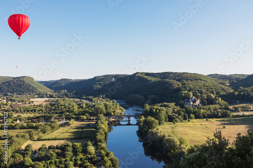 Red hot air balloon flying against clear sky over Dordogne River