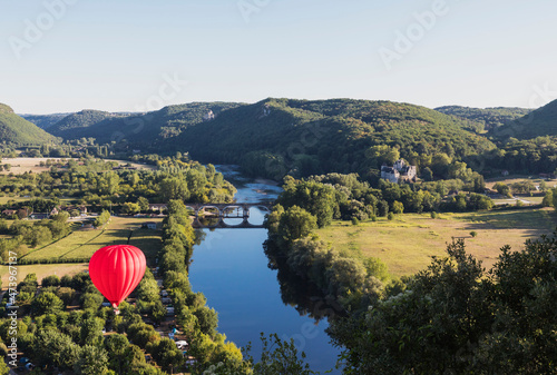 Red hot air balloon flying over Dordogne River
