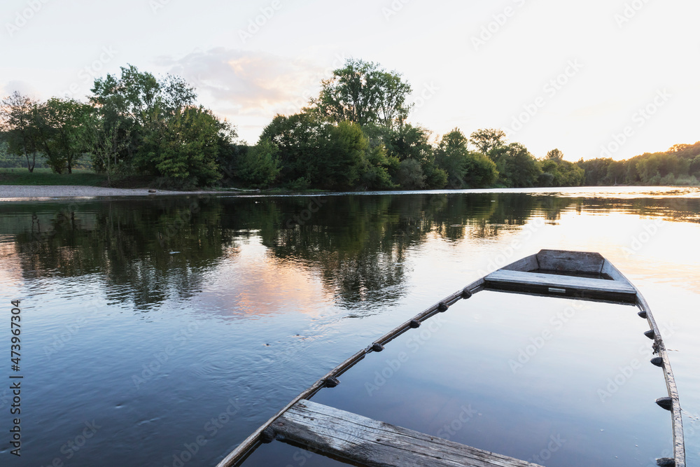 Sunken boat left at bank of Dordogne River at sunset Sunken boat left at bank of Dordogne River at sunset