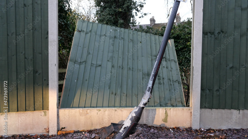 Fototapeta premium Broken fence panel with bent lamp post in the foreground