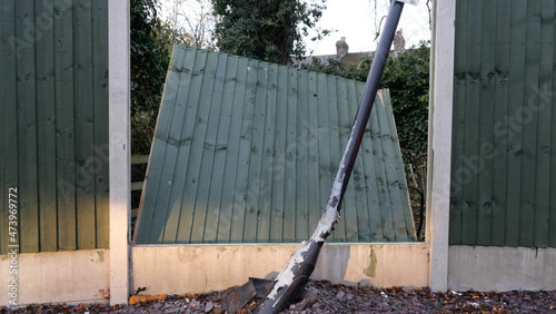 Obraz na plátne Broken fence panel with bent lamp post in the foreground