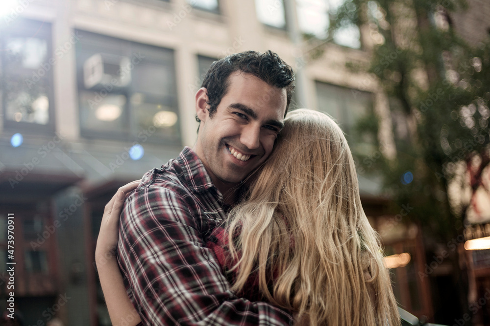 Smiling boyfriend embracing girlfriend in city Smiling boyfriend embracing girlfriend in city