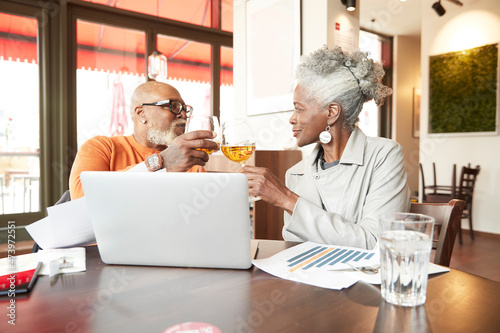 Businessman and senior female colleague toasting drinks in restaurant photo