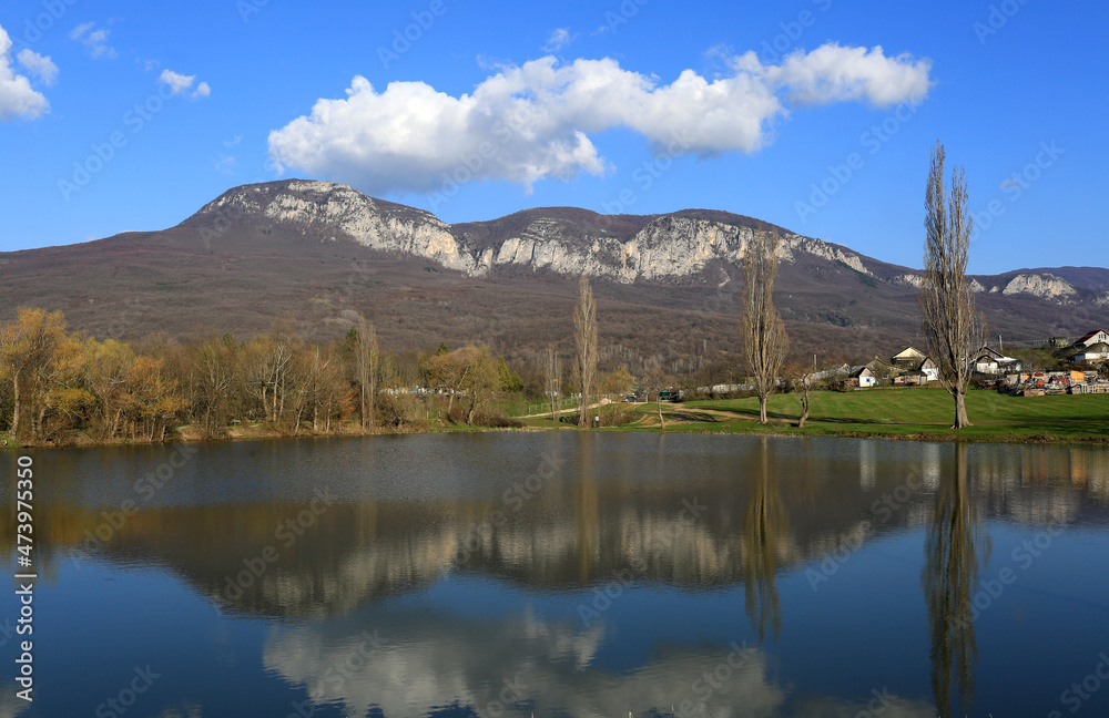 Spring landscape in the Crimea. Mountains and clouds in the blue sky reflected in the lake in the countryside