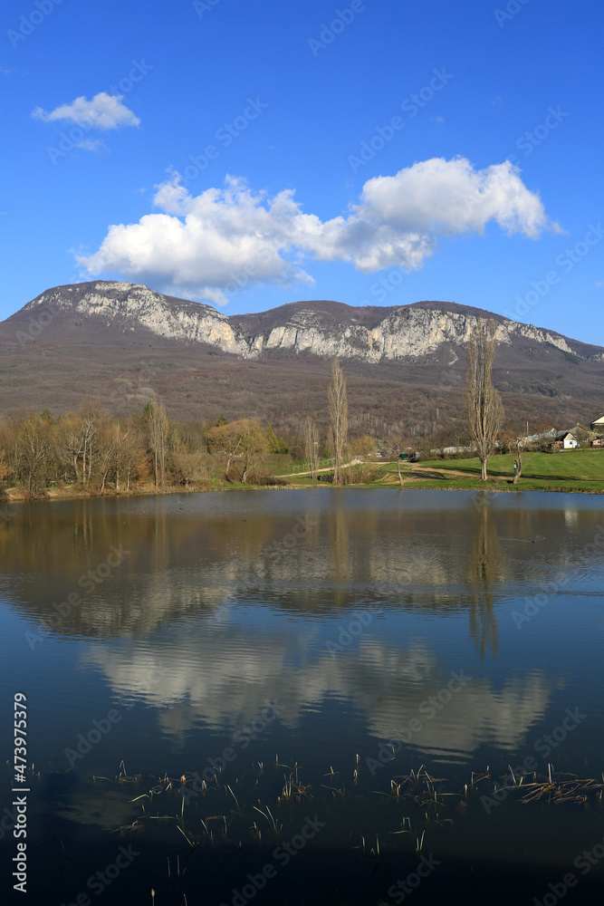 Beautiful spring landscape. Mountains and clouds are reflected in the lake on a sunny day