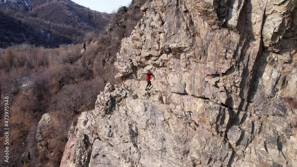 Rock climbing training on a steep slope in the mountains. The view from the drone. A group of people climb to the top of cliff. Brave girls and boys are looking for a trail on a cliff. Extreme sports Rock climbing training on a steep slope in the mountains. The view from the drone. A group of people climb to the top of cliff. Brave girls and boys are looking for a trail on a cliff. Extreme sports