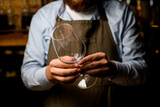 selective focus of male bartender hands gently holding an empty wine goblet glass.