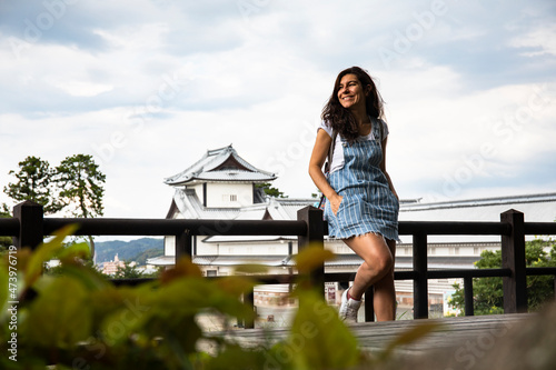 Japan, Ishikawa Prefecture, Kanazawa, Portrait of young woman leaning on railing against Kanazawa Castle photo