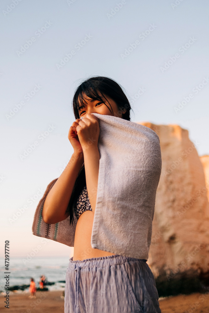 Young woman with bangs wrapped in towel standing at beach Young woman with bangs wrapped in towel standing at beach