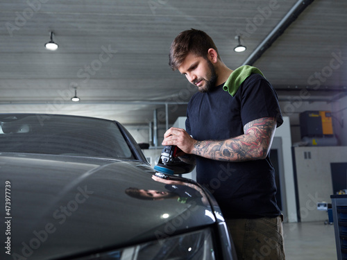 Technician polishing car with equipment at garage