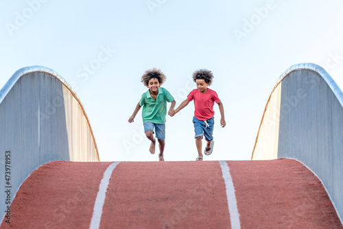 Boys with holding hands running on footbridge