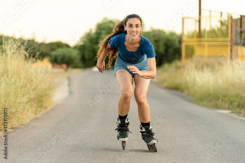 Smiling young woman roller skating on road
