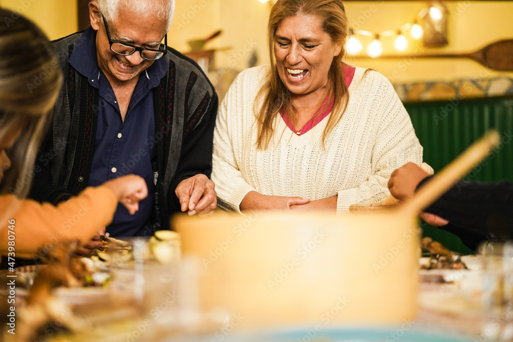 Happy latin family cooking together during dinner time at home - Focus on grandmother face Happy latin family cooking together during dinner time at home - Focus on grandmother face
