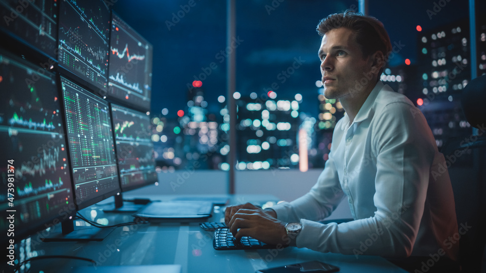 Fototapeta premium Financial Analyst Working on a Computer with Multi-Monitor Workstation with Real-Time Stocks, Commodities and Exchange Market Charts. Businessman Works in Investment Bank Downtown Office at Night.