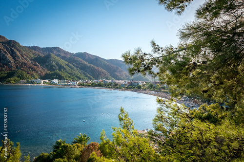 Summer landscape on the Mediterranean coast in Turkey. View of Icmeler beach  bay and mountains through pine branches