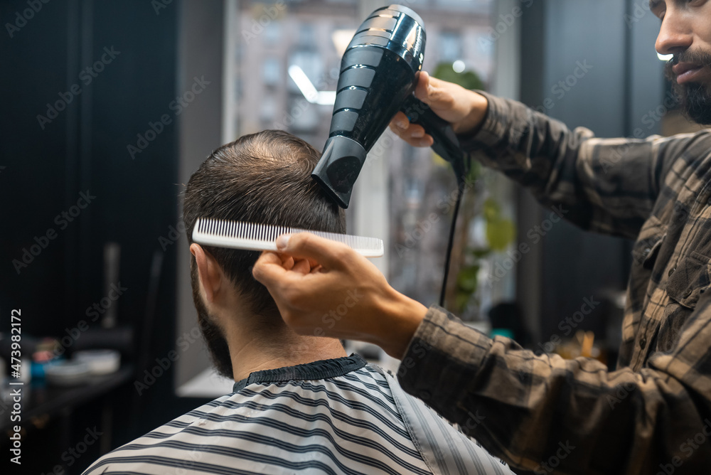 The master in the barbershop is styling the client's hair