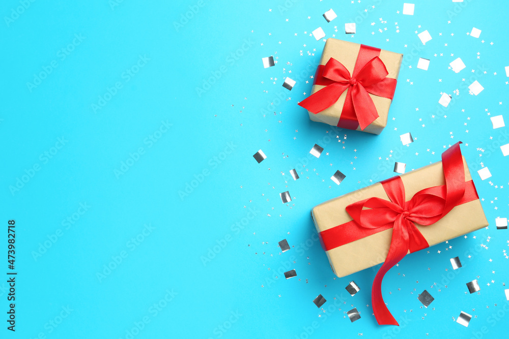 Gift boxes and shiny confetti on light blue background, flat lay. Space for text