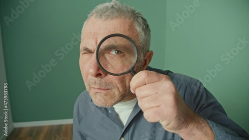 Alarmed Man Looking Suspiciously Through a Magnifying Glass. A Frightened Person Acting Strangely Due To Conspiracy Theories, 5G Waves, Mind Control and Human Control. Mental Health. photo