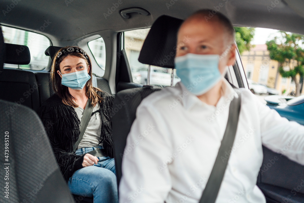 Taxi driver in a mask with a client on the back seat wearing mask Taxi driver in a mask with a client on the back seat wearing mask