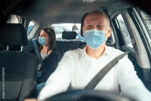 Photo Taxi driver in a mask with a client on the back seat wearing mask