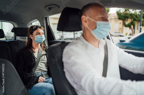 Taxi driver in a mask with a client on the back seat wearing mask © eunikas