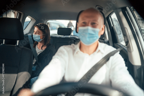 Taxi driver in a mask with a client on the back seat wearing mask © eunikas