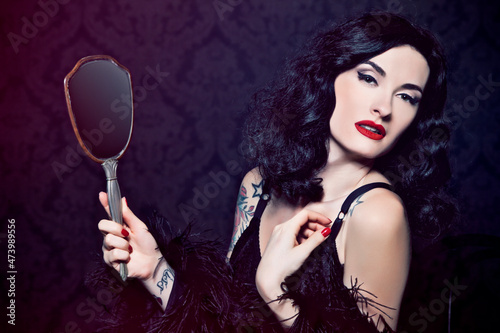 Foto Retro burlesque diva with tattoes holding a mirror