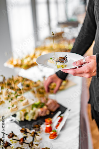 man hands take a snack and put it on plate. buffet in a restaurant