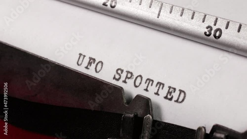 Typing a report of the sighting of a UFO an unidentified flying object on an old manual typewriter. An alien spacecraft spotted.