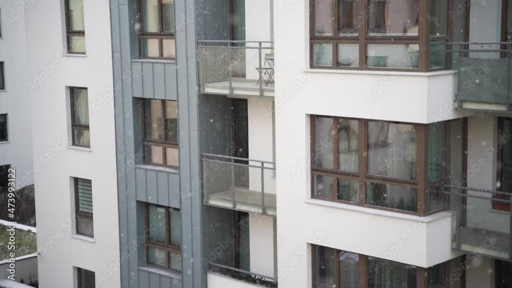 Slow-motion video of snow falling in the residential complex. Weather winter in the urban area. Snowing in front exterior modern condominium area. Slow-motion video of snow falling in the residential complex. Weather winter in the urban area. Snowing in front exterior modern condominium area.