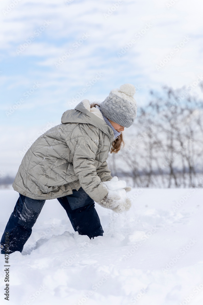 Funny girl throws snow up to the sky and rejoices. Happy children play snowballs, run, throw snow. Funny kids play games indoors in the winter with snow