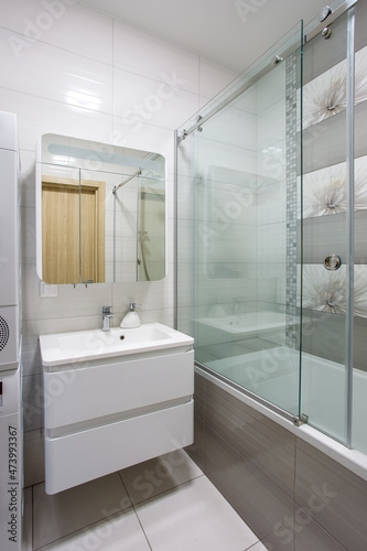 A modern bathroom with a white vanity, mirror, and hardware.