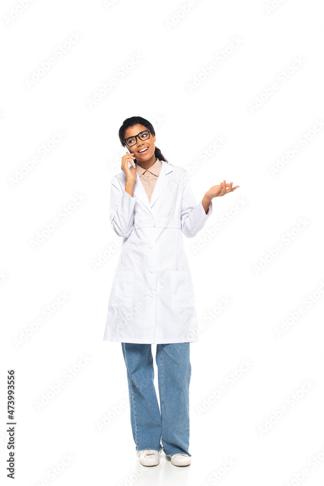Full length of smiling african american oculist talking on mobile phone on white background. Full length of smiling african american oculist talking on mobile phone on white background.