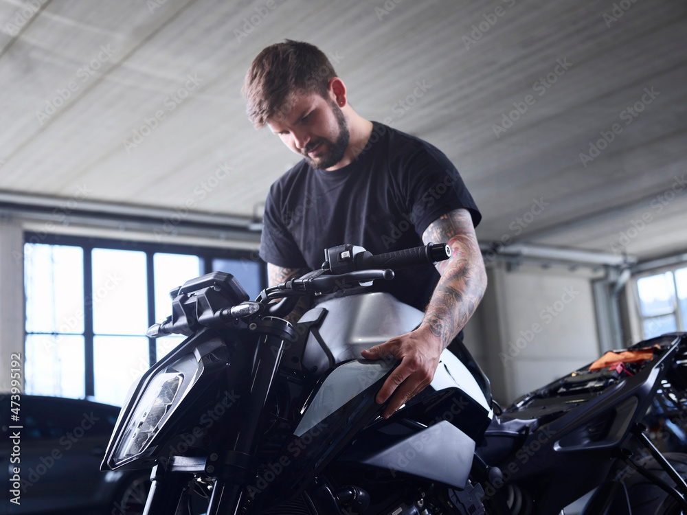 Technician checking motorcycle part at repair shop Technician checking motorcycle part at repair shop