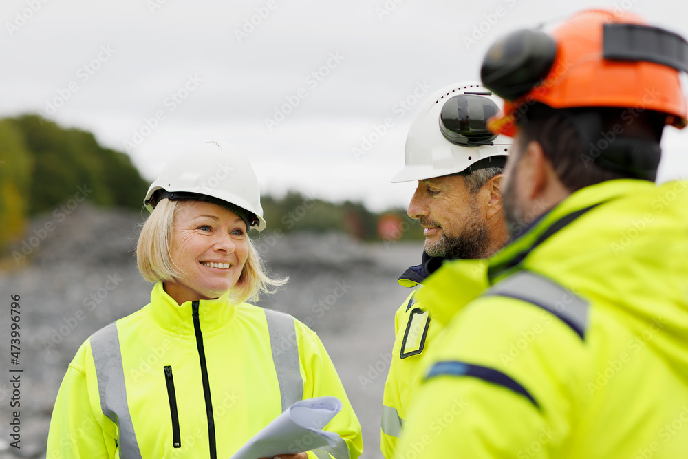 Engineers in reflective clothing discussing plans Engineers in reflective clothing discussing plans