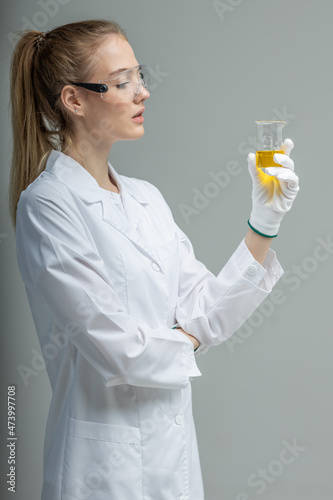 Chemical test tubes and flasks with petroleum products, the girl is a laboratory assistant, safety glasses