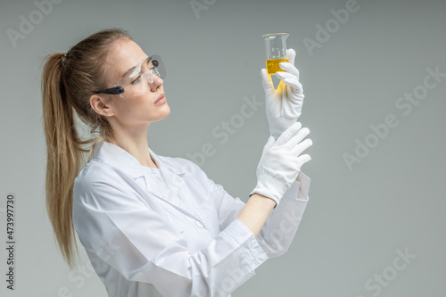 Chemical test tubes and flasks with petroleum products, the girl is a laboratory assistant, safety glasses