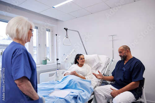 Female patient on hospital bed talking to nurse photo